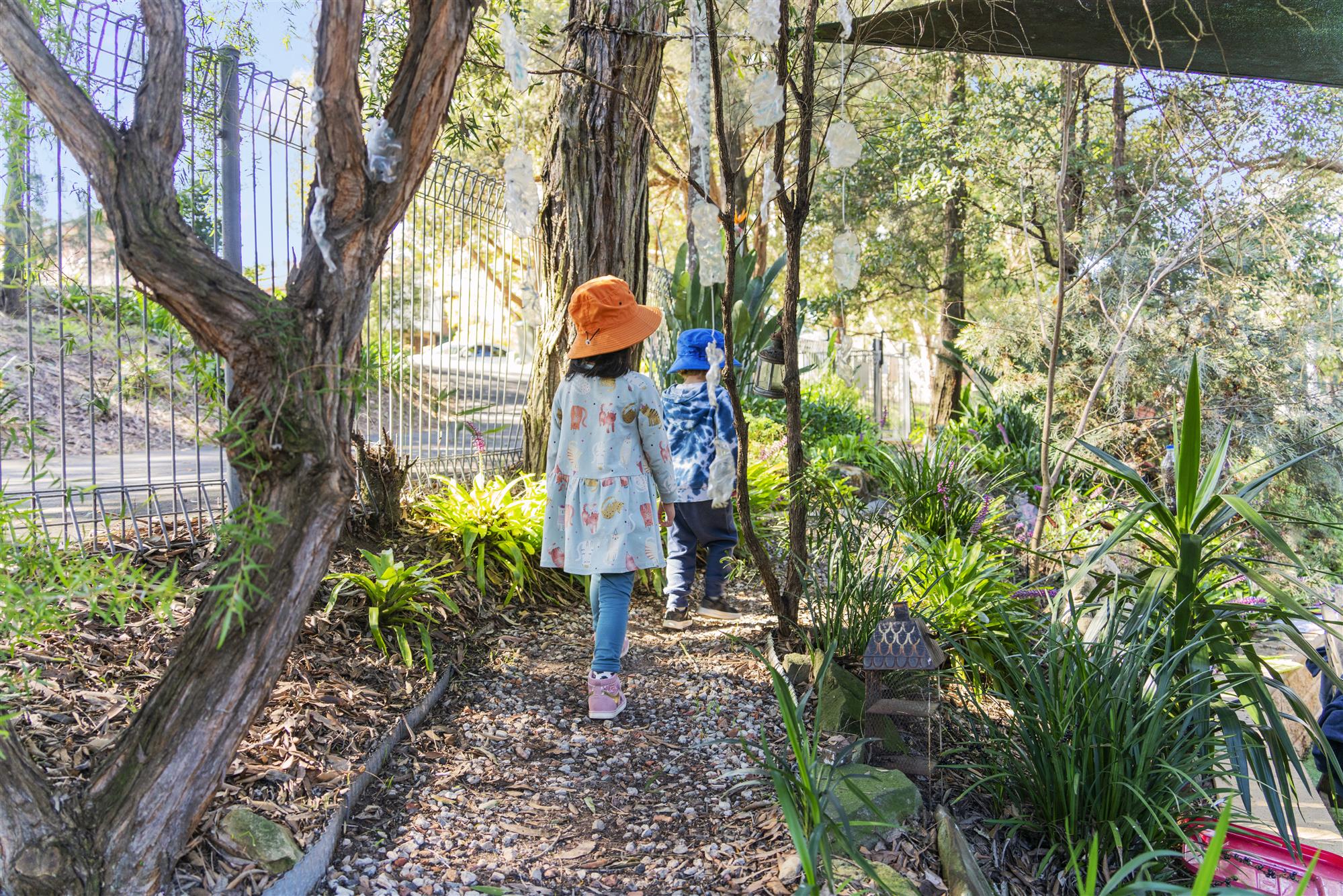 Shaded outdoor courtyard with timber picnic tables and garden at The Discovery House